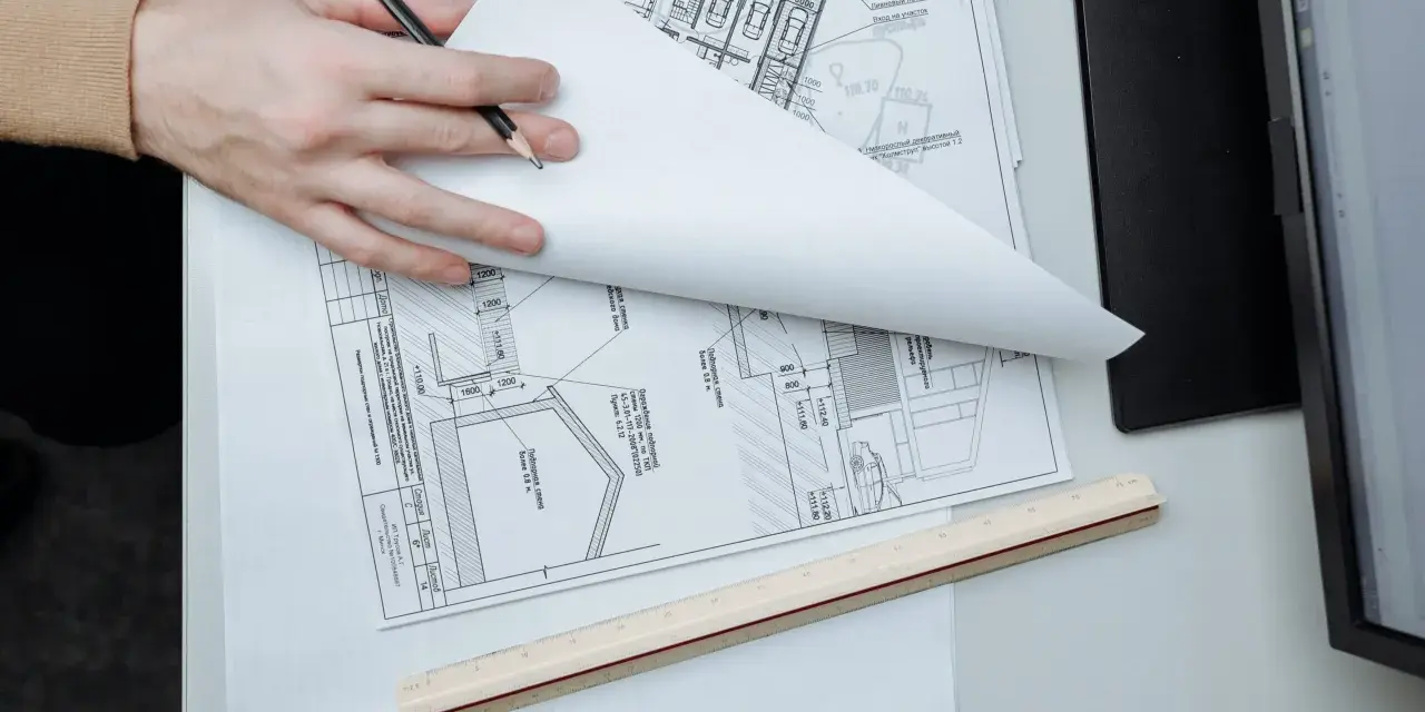 Manos revisando planos de construcción, un detalle que sugiere que se puede escriturar sin cédula de habitabilidad.