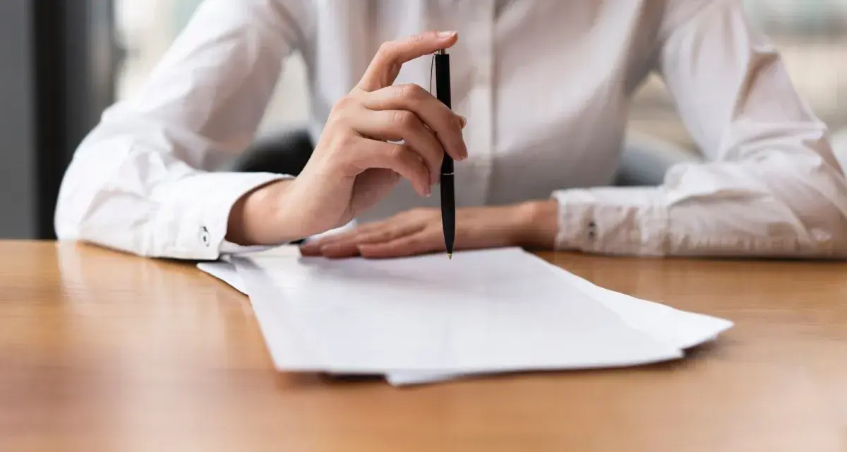 Mano con bolígrafo sobre papeles, revisando documentos. Quizás para resolver el lío de que he heredado una casa sin escrituras.