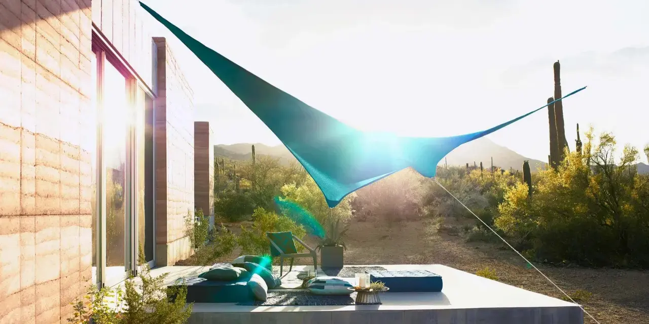 Terraza moderna con toldos vegetales que protegen del sol del desierto. Muebles cómodos y cactus al fondo.