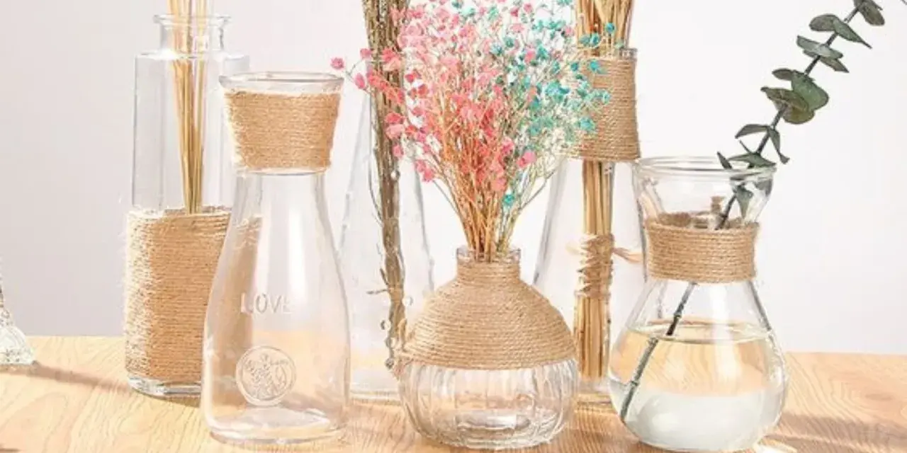 Botellas de cristal decoradas con cuerda, con flores secas y una rama de eucalipto.