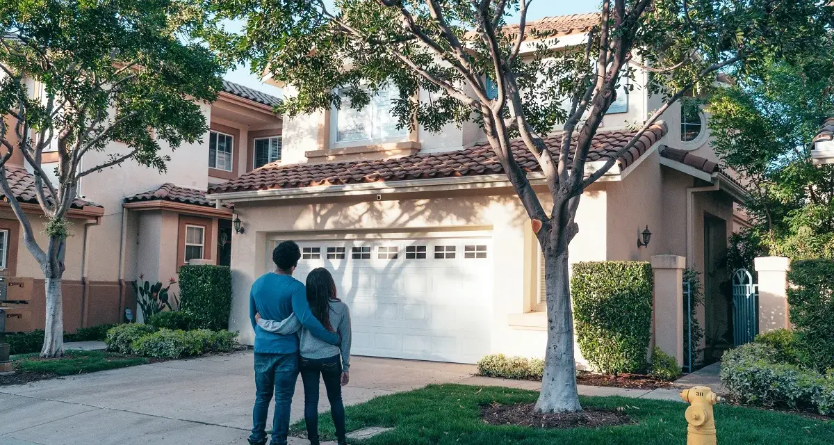 Pareja joven contempla su nueva casa a nombre de dos personas no casadas, un futuro compartido.