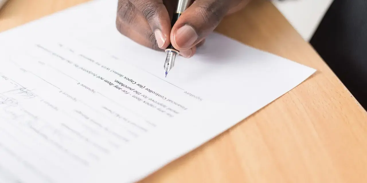 Mano firmando un documento legal. Se puede escriturar una casa a nombre de otra persona mediante este tipo de acuerdos.