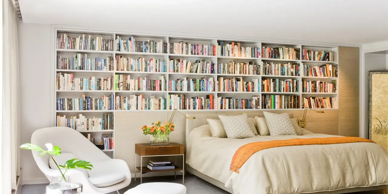 Dormitorio con una pared entera de estanterías llenas de libros, creando un ambiente acogedor en estas casas con biblioteca.