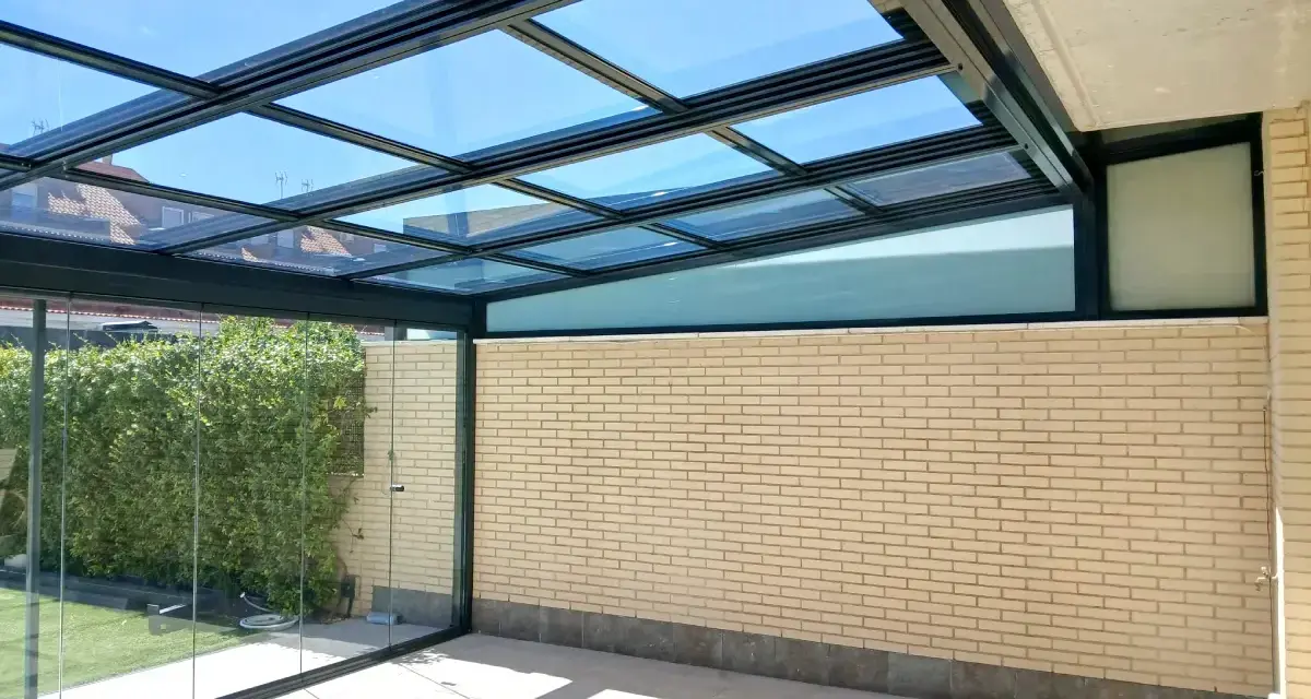 Un moderno montera patio interior con techo de cristal y paredes de ladrillo claro, ideal para disfrutar del exterior.