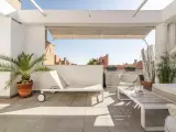 Encantadora decoracion terrazas aticos: tumbona, mesa de centro, sillón y plantas crean un oasis urbano.