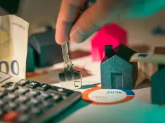 Llaves, dinero y casas en miniatura sobre un gráfico. ¿Es posible empadronarse sin contrato de alquiler?