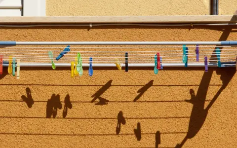 Tendedero exterior con pinzas de colores. Ideas para secar la ropa al sol, creando sombras divertidas en la pared.