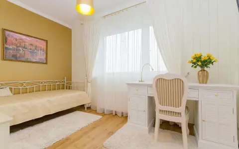 Dormitorio con paredes doradas, cama blanca y escritorio. Los colores que combinan con el amarillo en paredes son el blanco y los tonos tierra, creando un ambiente cálido y luminoso.