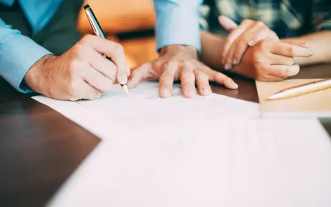 Manos firmando un contrato de alquiler con bolígrafo.