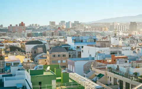 Vista aérea de tejados y edificios de una ciudad española bajo un cielo azul claro.