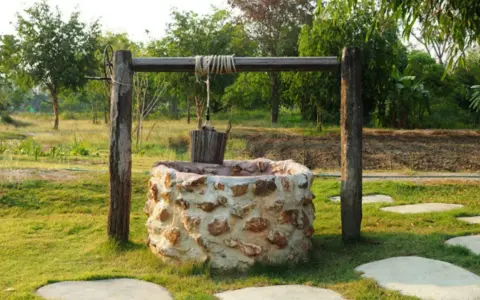 Pozo de piedra con cubo de madera colgando. Interesado en cuanto cuesta hacer un pozo así.