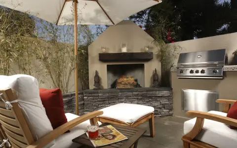 Un patio privado con chimenea, parrilla y cómodos asientos bajo sombrilla. Ideal para techar patio comunitario de uso privativo.