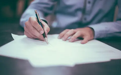 Persona firmando un documento. La pregunta clave es: ¿cuánto tarda en llegar una escritura original?