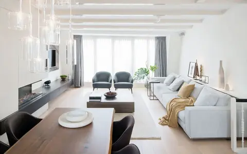 Elegante salón comedor dos ambientes con chimenea, sofás grises, mesa de centro y comedor de madera.