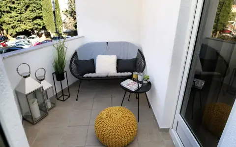 Acogedor rincón con sofá, cojines, mesita y puf amarillo. Dos faroles decoran estas terrazas pequeñas con encanto.