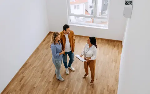 Pareja joven discutiendo con agente inmobiliaria sobre cómo comprar una casa con aportaciones diferentes.