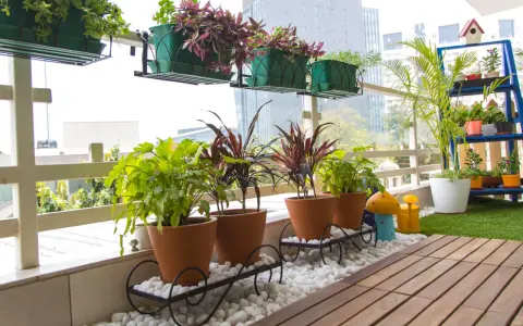 Balcón lleno de plantas en macetas, ideal para decorar terrazas barato. Césped artificial y suelo de madera completan el espacio.
