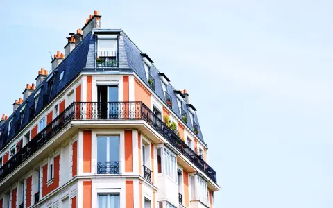 Edificio parisino con tejado mansarda y balcones de hierro forjado. Las fachadas naranjas y blancas, con chimeneas, parecen fuera de ordenación por su diseño único.