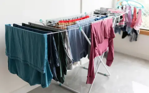 Tendedero desplegado con ropa de varios colores, una solución práctica para tender la ropa en un piso sin terraza.