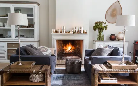 Ideas para decorar la repisa de una chimenea: velas, piñas y un jarrón con ramas secas crean un ambiente acogedor.