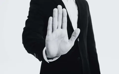 Mano extendida en señal de alto, con un traje oscuro. Representa el derecho de reversión, un límite claro.