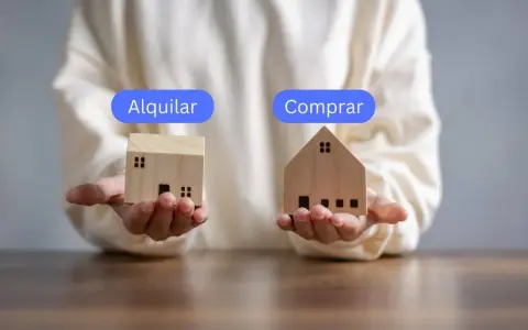 Manos sostienen casas de madera, una con "Alquilar" y otra con "Comprar", planteando la duda de si vivir de alquiler toda la vida es la mejor opción.