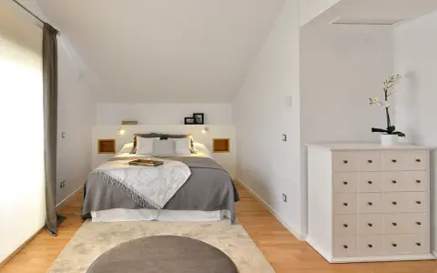 Habitación hermanos poco espacio, con cama doble, alfombra y cómoda blanca.
