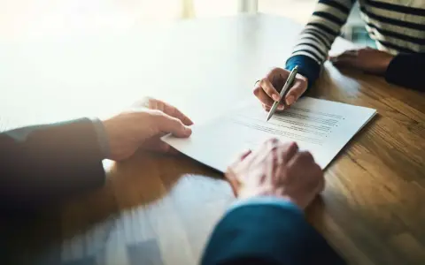 Manos firmando un contrato de alquiler de piso. Los padres avalan el alquiler.