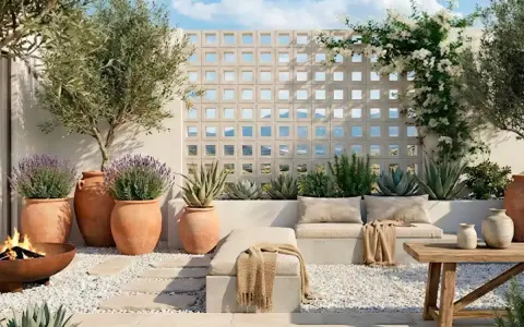 Terraza con asientos, plantas en macetas, un fuego y una pared de bloques decorativa.