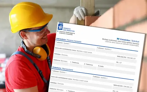 Obrero con casco amarillo sonríe mientras revisa un formulario de solicitud de licencia de obra menor en edificios residenciales.