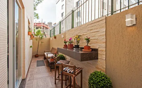 Un balcón acogedor con muebles de madera, plantas y un estante de granito. Ideal para disfrutar de pequeños patios.