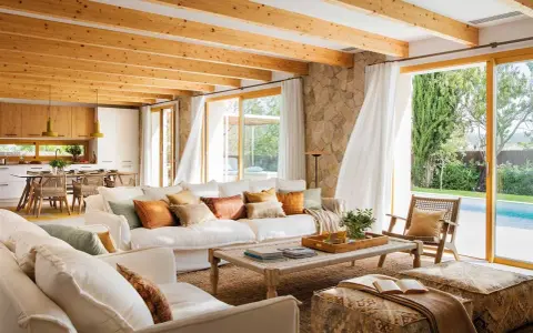 Salones blancos y madera con vigas expuestas, sofás cómodos y vistas a una piscina.