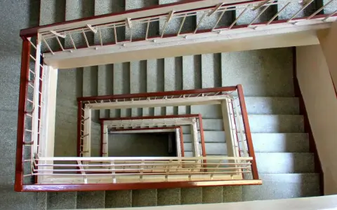 Vista cenital de un **rellano edificio** con escaleras en espiral, barandillas de metal y hormigón.