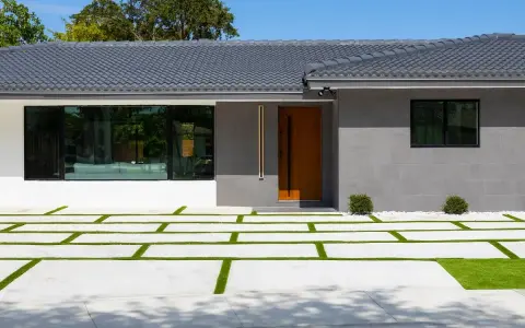 Casa moderna con entrada de madera y ventanal. El camino de acceso combina cemento y césped, ideal si me separo y quiero quedarme el piso.