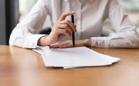 Mano con bolígrafo sobre papeles, revisando documentos. Quizás para resolver el lío de que he heredado una casa sin escrituras.