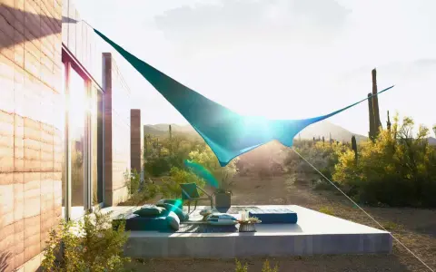 Terraza moderna con toldos vegetales que protegen del sol del desierto. Muebles cómodos y cactus al fondo.