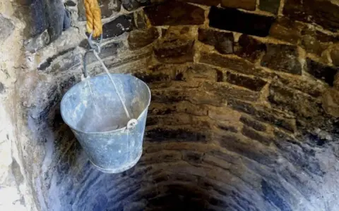 Un cubo cuelga de una cuerda en un pozo de piedra. ¡Qué útil sería si pudiera hacer un pozo en mi parcela!