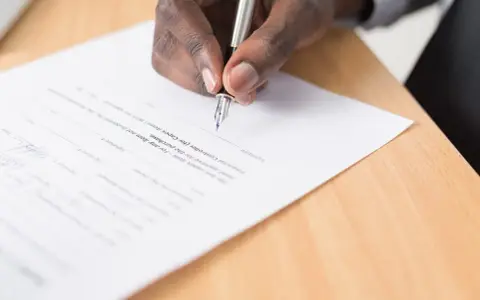 Mano firmando un documento legal. Se puede escriturar una casa a nombre de otra persona mediante este tipo de acuerdos.