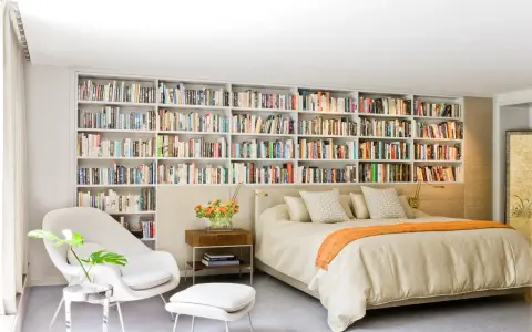 Dormitorio con una pared entera de estanterías llenas de libros, creando un ambiente acogedor en estas casas con biblioteca.