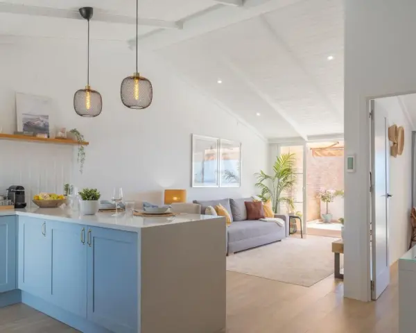 Cocina y sala de estar luminosas, perfectas para decorar casa playa poco presupuesto. Muebles claros, plantas y detalles náuticos crean un ambiente fresco.