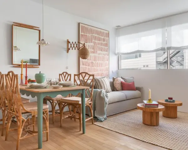 Ideas para decorar un piso pequeño con poco dinero: mesa de comedor de ratán, sofá acogedor y arte de pared llamativo.