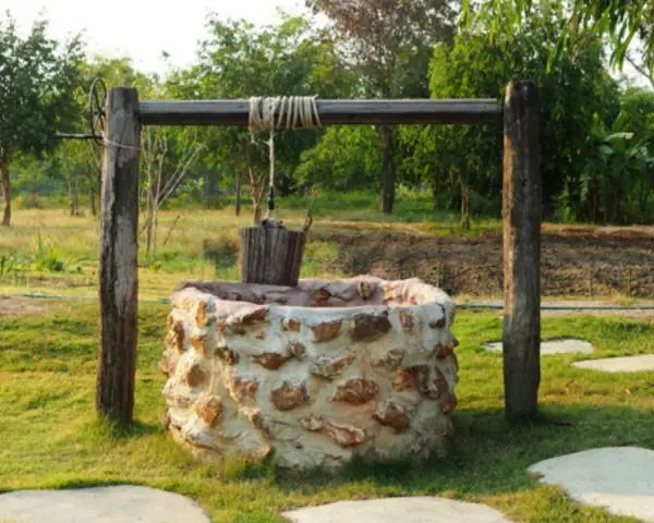 Pozo de piedra con cubo de madera colgando. Interesado en cuanto cuesta hacer un pozo así.