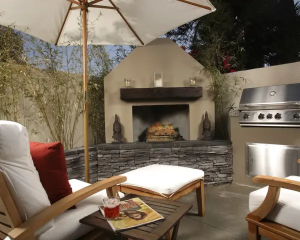 Un patio privado con chimenea, parrilla y cómodos asientos bajo sombrilla. Ideal para techar patio comunitario de uso privativo.