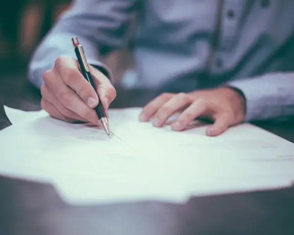 Persona firmando un documento. La pregunta clave es: ¿cuánto tarda en llegar una escritura original?