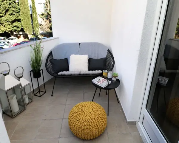 Acogedor rincón con sofá, cojines, mesita y puf amarillo. Dos faroles decoran estas terrazas pequeñas con encanto.