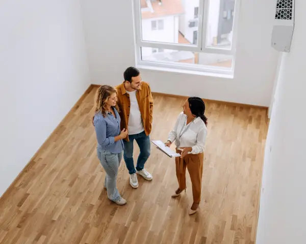 Pareja joven discutiendo con agente inmobiliaria sobre cómo comprar una casa con aportaciones diferentes.