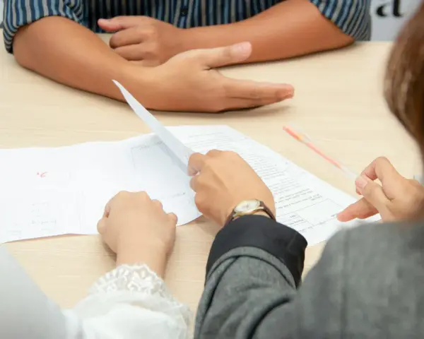 Personas revisando documentos, discutiendo cómo comprar casa sin escrituras.