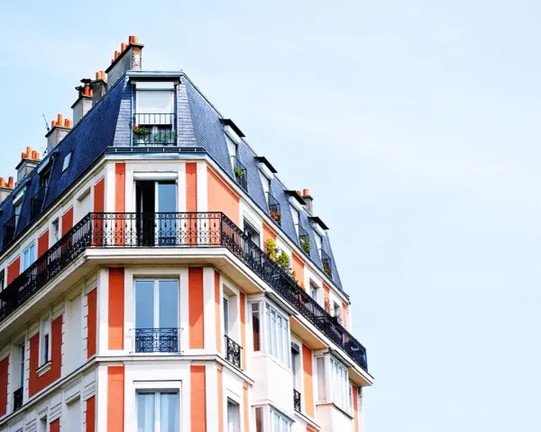 Edificio parisino con tejado mansarda y balcones de hierro forjado. Las fachadas naranjas y blancas, con chimeneas, parecen fuera de ordenación por su diseño único.