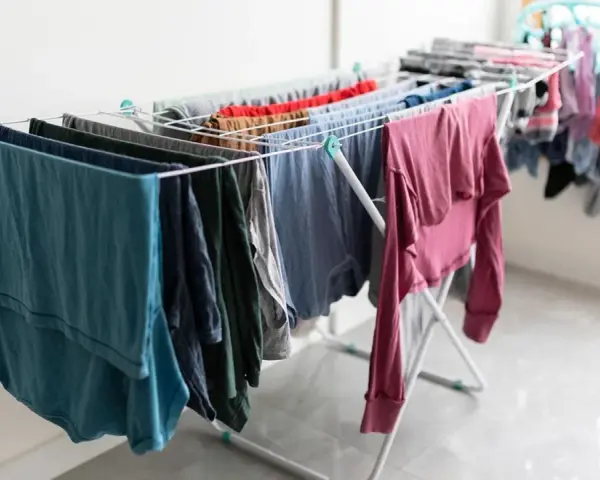 Tendedero desplegado con ropa de varios colores, una solución práctica para tender la ropa en un piso sin terraza.