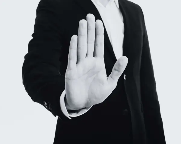Mano extendida en señal de alto, con un traje oscuro. Representa el derecho de reversión, un límite claro.